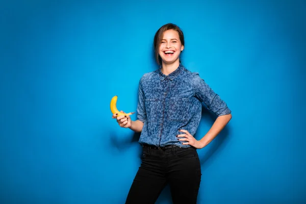 Mujer con plátano en manos sobre fondo azul —  Fotos de Stock