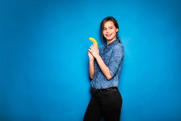 香蕉在蓝色背景上的手中的女人 — 图库照片