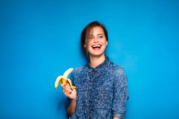 Mujer con plátano en manos sobre fondo azul —  Fotos de Stock