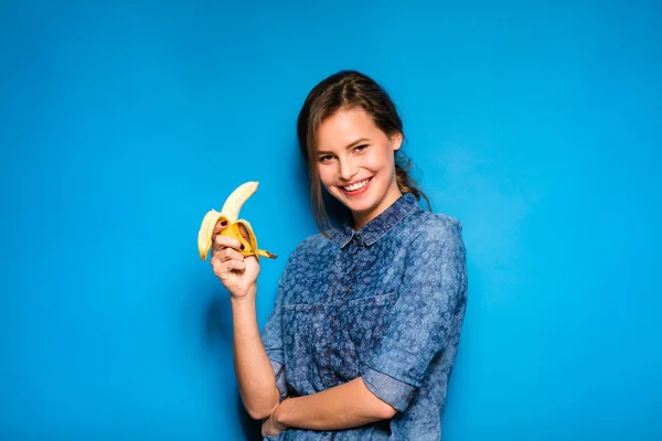 Mujer con plátano en manos sobre fondo azul — Foto de Stock