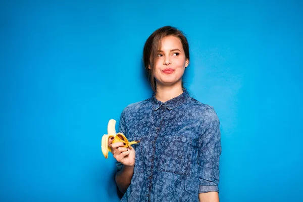 Mujer con plátano en manos sobre fondo azul — Foto de Stock