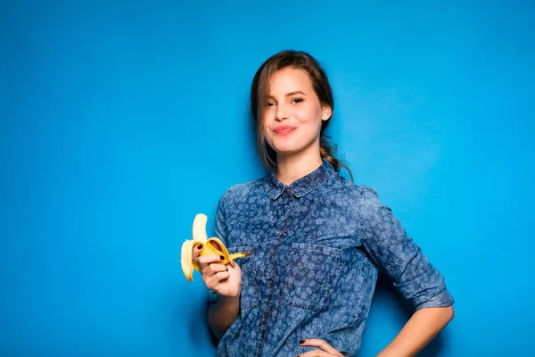 Mujer con plátano en manos sobre fondo azul — Foto de Stock