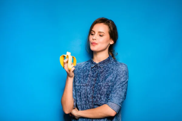 Vrouw met banaan in handen op blauwe achtergrond — Stockfoto