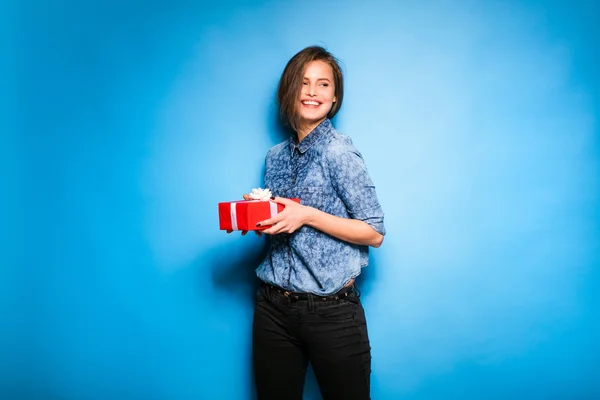 Mujer joven sosteniendo regalo rojo en las manos — Foto de Stock