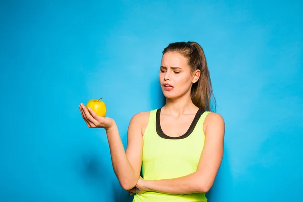 Pretty woman in sport equipment holding an apple in hand — Stock Photo, Image