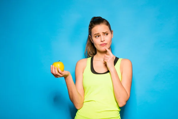 Pretty woman in sport equipment holding an apple in hand — Stock Photo, Image