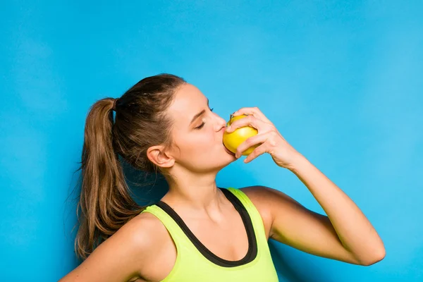 Pretty woman in sport equipment eating an apple in hand — Stock Photo, Image