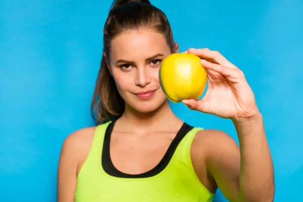 Mulher bonita em equipamento desportivo segurando uma maçã na mão — Fotografia de Stock