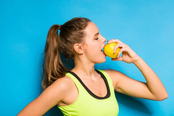 Vacker kvinna i sportutrustning äta ett äpple i handen — Stockfoto