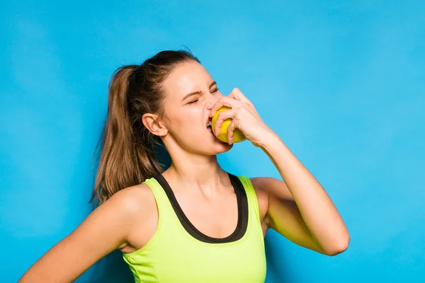 Pretty woman in sport equipment eating an apple in hand — Stock Photo, Image