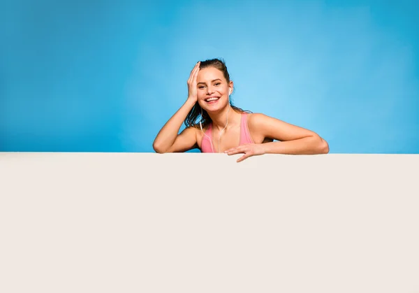 Mujer bonita con auriculares sobre un panel vacío — Foto de Stock