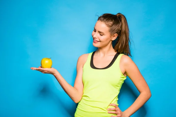 Hübsche Frau in Sportausrüstung mit einem Apfel in der Hand — Stockfoto