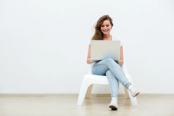 Mujer soltera sentada en silla blanca con portátil — Foto de Stock