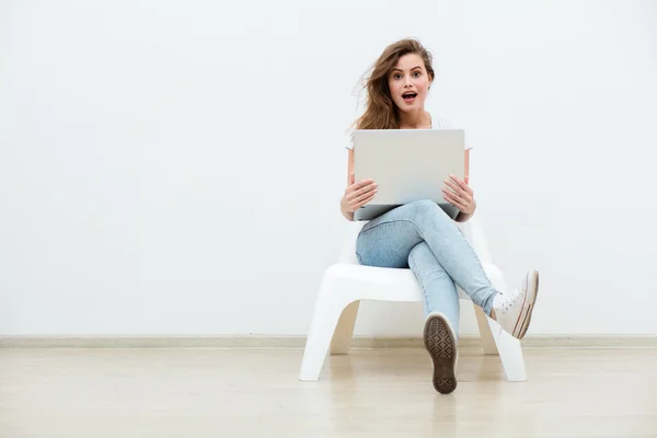 Alleinstehende Frau sitzt auf weißem Stuhl mit Laptop — Stockfoto