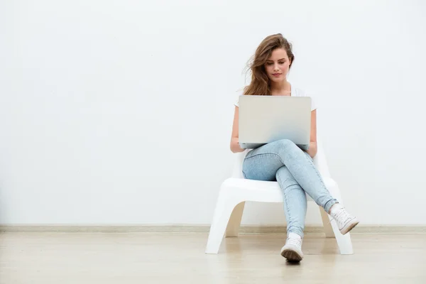 Mujer soltera sentada en silla blanca con portátil — Foto de Stock