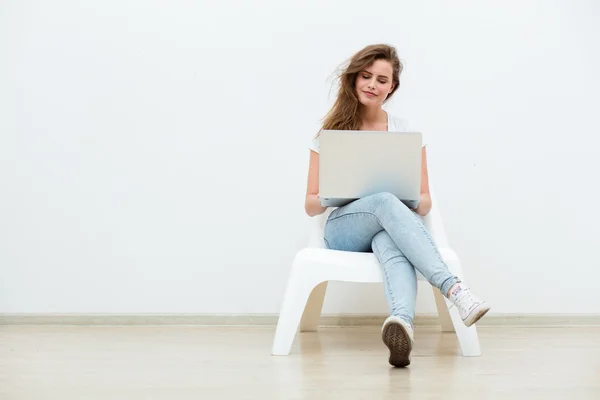 Single woman sitting on white chair with laptop — Stock Photo, Image