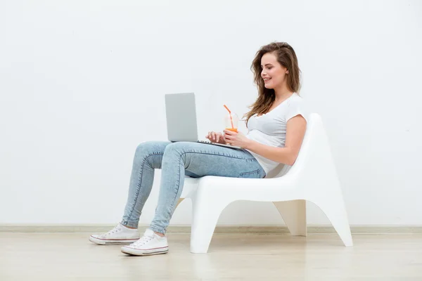 Mujer soltera sentada en silla blanca con portátil — Foto de Stock