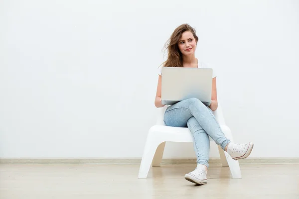 Žena sedící na bílé křeslo s notebookem — Stock fotografie