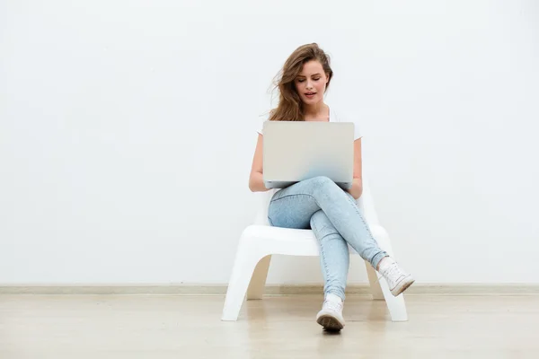 Mujer soltera sentada en silla blanca con portátil — Foto de Stock