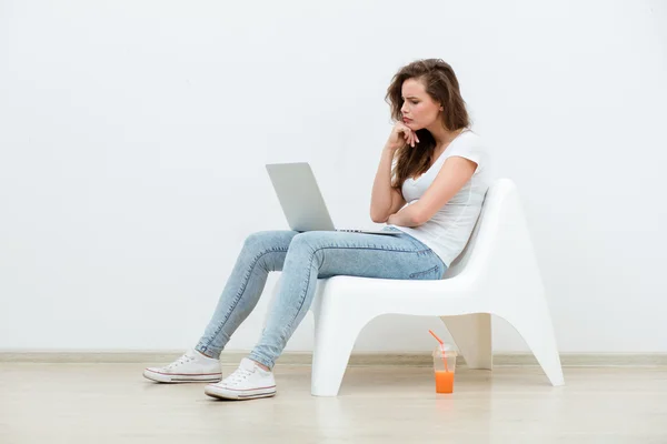 Mujer soltera sentada en silla blanca con portátil —  Fotos de Stock