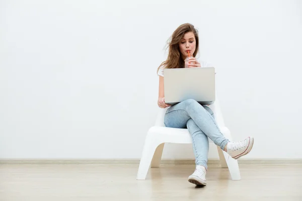 Alleinstehende Frau sitzt auf weißem Stuhl mit Laptop — Stockfoto