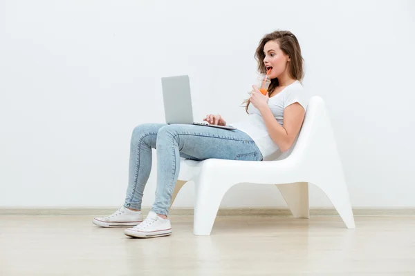 Alleinstehende Frau sitzt auf weißem Stuhl mit Laptop — Stockfoto