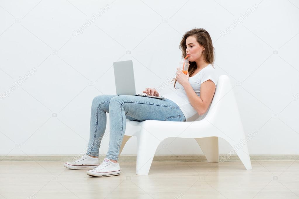 single woman sitting on white chair with laptop