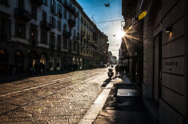 Milan, İtalya - 30 Aralık 2017 - Peolpe arka planda parlak güneşle Milano 'da sokakta yürüyor
