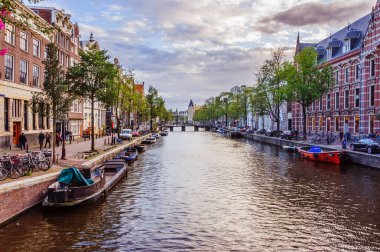 Amsterdam, Hollanda - 13 Eylül 2017 - Amsterdam 'daki kanallardan birinde eski tekneler ve arka planda bulutlu gökyüzü