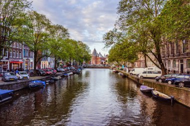 Amsterdam, Hollanda - 13 Eylül 2017 - Amsterdam 'daki kanallardan birinde eski tekneler ve arka planda bulutlu gökyüzü