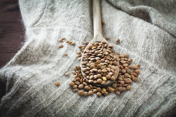 Raw lentils over spoon and woolen — Stock Photo, Image