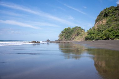 Kaya oluşumları ve ağaçlarla ıssız bir sahil. Kosta Rika
