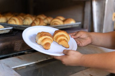 Fırının önündeki bir insanın elinde iki kruvasan.