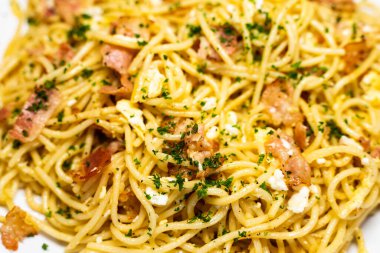 Beyaz bir tabakta servis edilen spagetti carbonara 'nın yakın görüntüsü