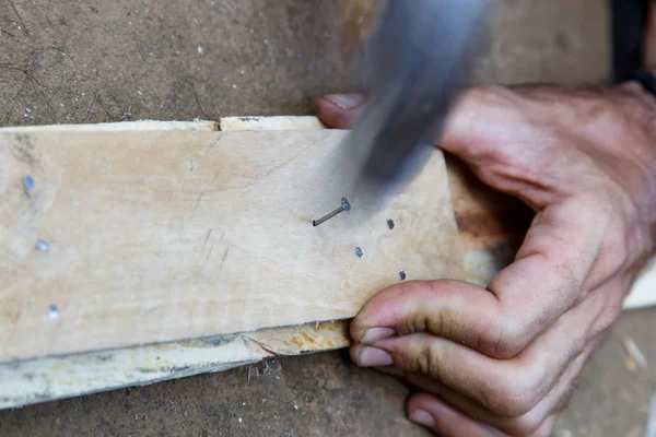 用锤子在木头上工作的手 — 图库照片