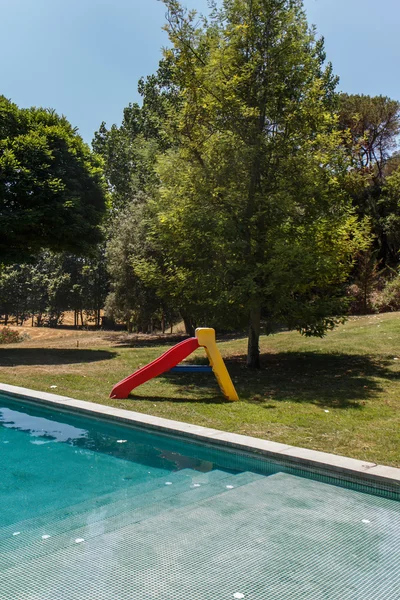 Πλαστική τσουλήθρα και μια πισίνα μέσα σε κήπο — Φωτογραφία Αρχείου