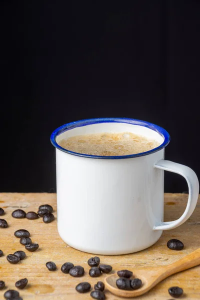 コーヒー コーヒー豆 木製のスプーン付きのクローズアップ白いカップ 素朴なテーブルと黒の背景に — ストック写真