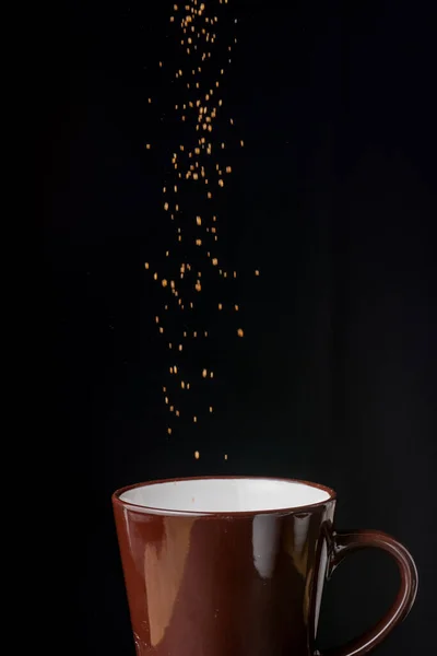 Kahverengi kahve fincanının kahverengi şekerli görüntüsü, siyah arkaplanda, dikey olarak, kopyalama alanı ile birlikte