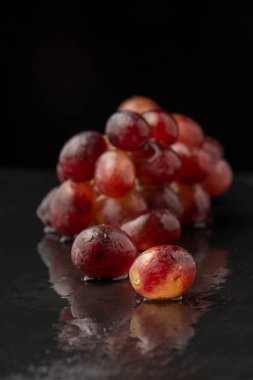Yansıma, seçici odak, siyah arkaplan, dikey arkaplan üzerine kırmızı sugranineteen üzümlere yakın çekim