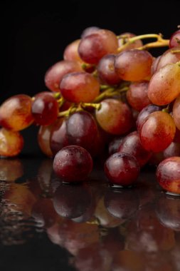 Yansıma, seçici odak, siyah arkaplan, dikey arkaplan üzerine kırmızı sugranineteen üzümlerin görünümü