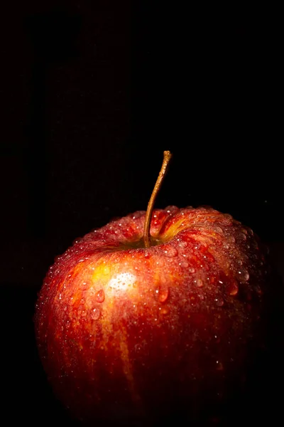 Su damlalı kırmızı elmanın görüntüsü, seçici odaklı, siyah arkaplan, dikey, kopyalama alanı ile aydınlatılmış 