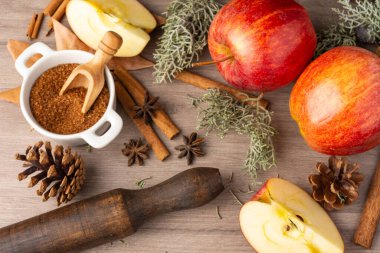 Tarçın çubuklu kırmızı kraliyet gala elmalarının havadan görünüşü, kahverengi şeker, merdane ve sonbahar yaprakları, seçici odak, tahta masa, yatay