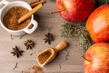 Tarçın çubuklu üç kırmızı kraliyet elması, kahverengi şeker ve sonbahar yapraklı hava manzaralı, seçici odaklı, tahta tahtada, yatay