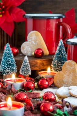 Kırmızı kupa, zencefilli kurabiyeler, mumlar ve kırmızı Noel süslemeleri, seçici odaklı, dikey