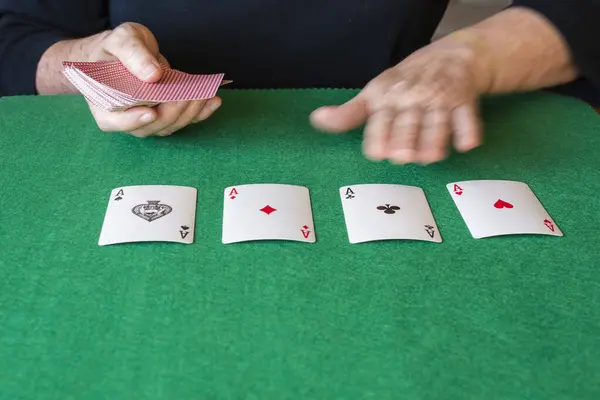 Top view of woman\'s hands, one of them in motion, making a solitaire with poker cards, on green playing mat, horizontal, with copy space