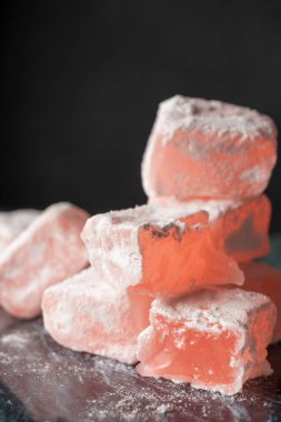 Türk Lokumu 'na güllerle yakın çekim, istiflenmiş, mavi mermer üzerine şeker, seçici odak, siyah arkaplan, dikey,