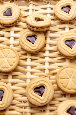 Kalp şeklinde kurabiyelerin ve çilek reçelinin üst görüntüsü, sepetin üzerinde, Sevgililer Günü için, dikey olarak