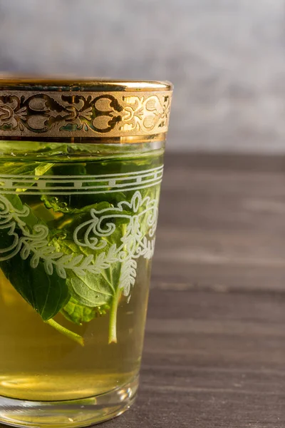 Yarım bardak, çay ve nane ile süslenmiş koyu ahşap masa, dikey olarak, kopyalama alanı ile.