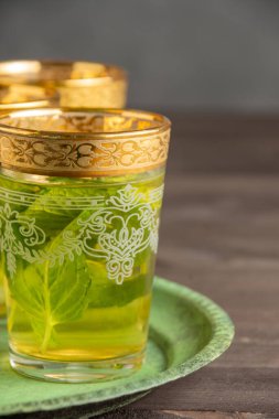 Süslü naneli çay bardaklarını yakın plan, yeşil tabakta, seçici odak, koyu tahta masa, koyu arka plan, dikey