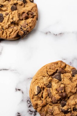 Beyaz mermer masa üzerinde iki çikolatalı kurabiye yakın plan, seçici odak, dikey, kopyalama alanı ile